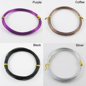 Op de afbeelding: Vier spoelen draad in verschillende kleuren: paars, koffie, zwart en zilver. Elke spoel is tot een cirkel gewikkeld.