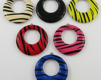 May include: Six wooden rings with a zebra print design in different colors: black, white, yellow, red, pink, and blue. The rings have a hole in the center and are approximately 2 inches in diameter.