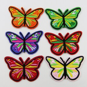 May include: Six embroidered iron-on patches featuring colourful butterfly designs. The butterflies are in various colours, including red, orange, yellow, green, blue, and purple.