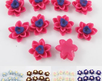 Puede incluir: Surtido de cabujones de resina en forma de flor de color rosa, blanco y morado. Los cabujones son de varios tamaños y formas, incluyendo una forma de estrella.