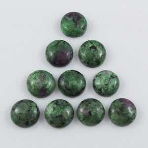 May include: Ten round green and pink gemstone cabochons, each with a unique pattern. The cabochons are arranged in a triangular shape.