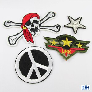 May include: Five embroidered iron-on patches. One patch features a white peace sign on a black background. Another patch features a white skull and crossbones with a red bandana. A third patch features a green, red, and yellow military-style patch with three stars and the letters LHK. A fourth patch features a white star.