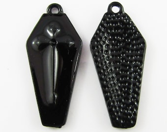 May include: Two black metal coffin-shaped charms with a cross on one side and a textured surface on the other.