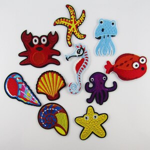 May include: A set of 10 colorful iron-on patches featuring various sea creatures, including a starfish, crab, jellyfish, seahorse, octopus, seashells, and a fish. The patches are perfect for adding a whimsical touch to clothing, bags, or other fabric items.