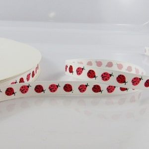 May include: White ribbon with a repeating pattern of red ladybugs. The ribbon is rolled up on a white spool.