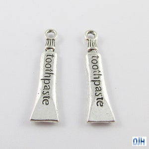 May include: Two silver charm pendants shaped like tubes of toothpaste with the word "toothpaste" engraved on them.