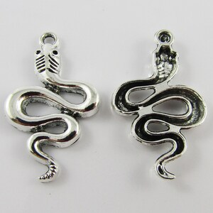Peut inclure: Deux breloques en forme de serpent argentées avec un design détaillé. Les breloques sont en forme de serpent avec la tête levée. Le serpent est enroulé en cercle. Les breloques sont parfaites pour la fabrication de bijoux ou pour ajouter à un porte-clés.