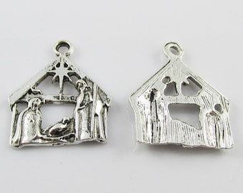 May include: Two silver-toned metal charms depicting a nativity scene. One charm features a detailed nativity scene with figures of Mary, Joseph, and the baby Jesus. The other charm has a cut-out nativity scene with the figures of Mary, Joseph, and the baby Jesus.