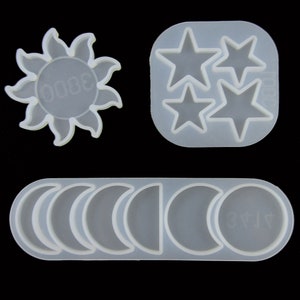 May include: A white silicone mould with three star shapes and a sun shape. There is also a separate mould with six crescent moon shapes.