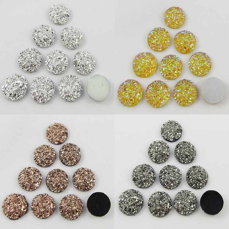 Puede incluir: Surtido de 12 cabochones redondos, de fondo plano, cubiertos de purpurina, en colores plata, oro y oro rosa. Los cabochons est&aacute;n dispuestos en tres grupos de cuatro, con cada grupo formando una forma triangular.