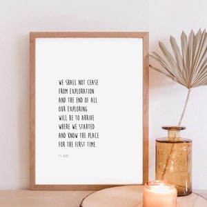Könnte beinhalten: Ein gerahmter Druck mit weißem Hintergrund und schwarzem Text. Der Text lautet: "We shall not cease from exploration and the end of all our exploring will be to arrive where we started and know the place for the first time." Der Text wird T.S. Eliot zugeschrieben.