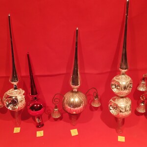 Peut inclure: Six d&eacute;corations de sommet d'arbre de No&euml;l en verre vintage dans diff&eacute;rents styles. Les d&eacute;corations sont en verre argent&eacute;, rouge et transparent. Certaines ont des cloches et d'autres ont une forme d'&eacute;toile. Les d&eacute;corations sont num&eacute;rot&eacute;es de 1 &agrave; 6.