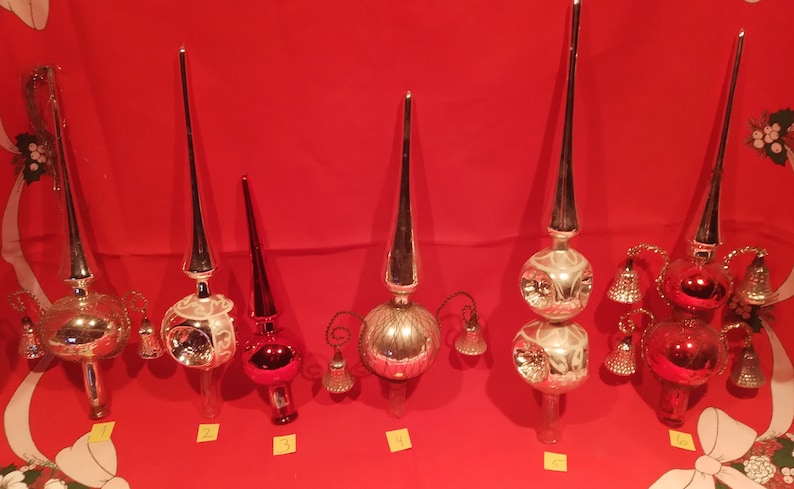 Peut inclure: Six d&eacute;corations de sommet d'arbre de No&euml;l en verre vintage dans diff&eacute;rents styles. Les d&eacute;corations sont en verre argent&eacute;, rouge et transparent. Certaines ont des cloches et d'autres ont une forme d'&eacute;toile. Les d&eacute;corations sont num&eacute;rot&eacute;es de 1 &agrave; 6.