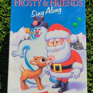 May include: A VHS tape titled "The Rudolph, Frosty & Friends Sing Along" featuring illustrations of Rudolph the Red-Nosed Reindeer, Frosty the Snowman, and Santa Claus. The tape is part of the Christmas Classics series, suitable for all ages.