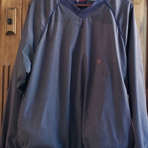 May include: A blue and white checkered long-sleeved shirt with a v-neck collar and a small logo on the left chest. The shirt is made by "Bugle Boy".