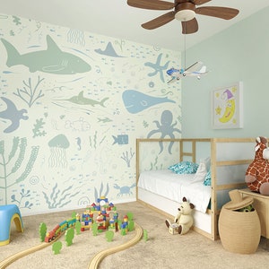 Pu&ograve; includere: Una camera da letto per bambini blu chiaro e verde con un letto, un set di treni giocattolo e un murale a parete con una variet&agrave; di creature marine.
