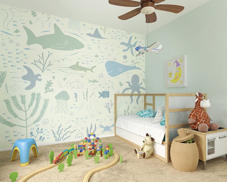 Pu&ograve; includere: Una camera da letto per bambini blu chiaro e verde con un letto, un set di treni giocattolo e un murale a parete con una variet&agrave; di creature marine.