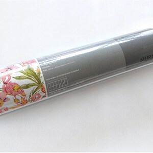 May include: A rolled up wallpaper mural with a pink flamingo and floral pattern. The label reads "MURAL'S" and includes the text "This mural is not considered to be repeat."