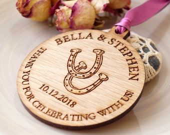 Könnte beinhalten: Ein runder Holzanhänger mit dem Text "Thank you for celebrating with us! Bella & Stephen 10.12.2018" und einem Paar Hufeisen.