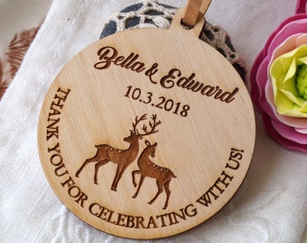 Könnte beinhalten: Ein runder Holzanhänger für eine Hochzeit mit einem Hirschdesign und den Namen "Bella & Edward" sowie dem Datum "10.3.2018" eingraviert. Der Text "THANK YOU FOR CELEBRATING WITH US!" ist ebenfalls eingraviert. Ein Lederband ist befestigt.