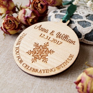 May include: A round wooden ornament with a snowflake design and the text "Anna & William 12.31.2017 Thank you for celebrating with us!"