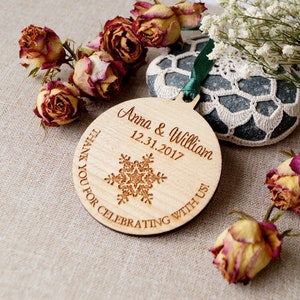 May include: A round wooden ornament with a snowflake design and the text "Anna & William 12.31.2017" and "Thank you for celebrating with us!"