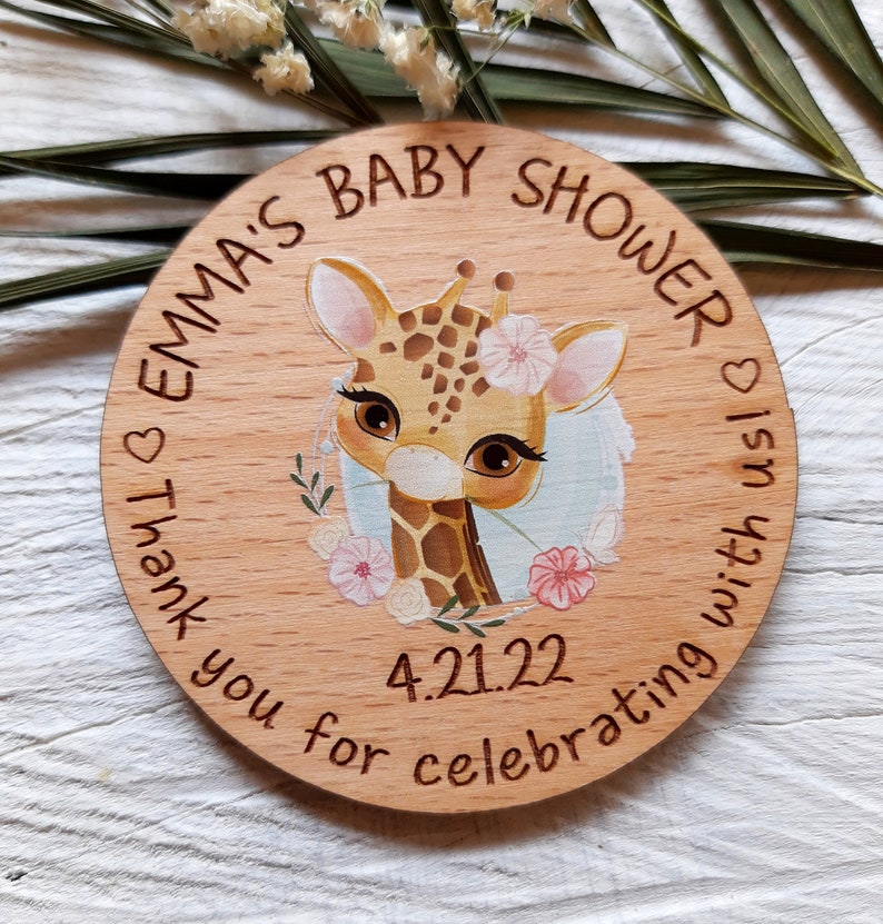 Peut inclure: Une pancarte ronde en bois avec une illustration de girafe et le texte "Emma's Baby Shower" et "Thank you for celebrating with us!" La date "4.21.22" est &eacute;galement incluse sur la pancarte.