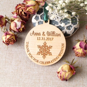 May include: A round wooden ornament with a snowflake design and the text "Anna & William 12.31.2017 Thank you for celebrating with us!"