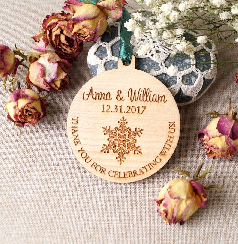 May include: A round wooden ornament with a snowflake design and the text "Anna & William 12.31.2017 Thank you for celebrating with us!"