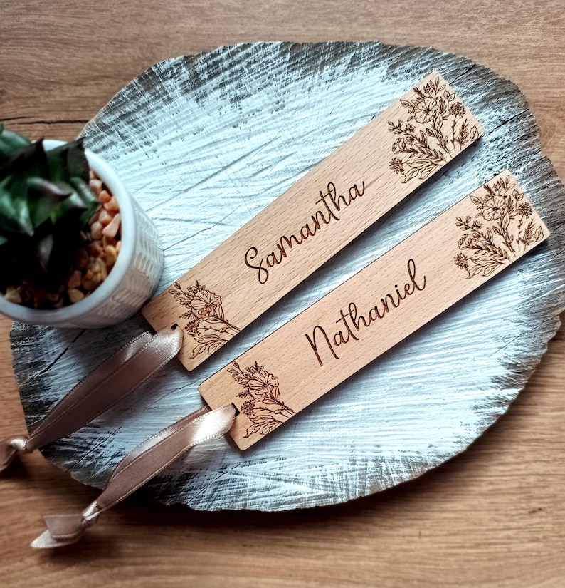 May include: Two wooden bookmarks with floral designs and personalized names, "Samantha" and "Nathaniel", with brown ribbon ties.