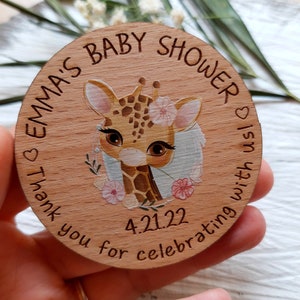 Peut inclure: Une pancarte ronde en bois avec une illustration de girafe et le texte "Emma's Baby Shower" et "Thank you for celebrating with us!" La date "4.21.22" est &eacute;galement incluse sur la pancarte.