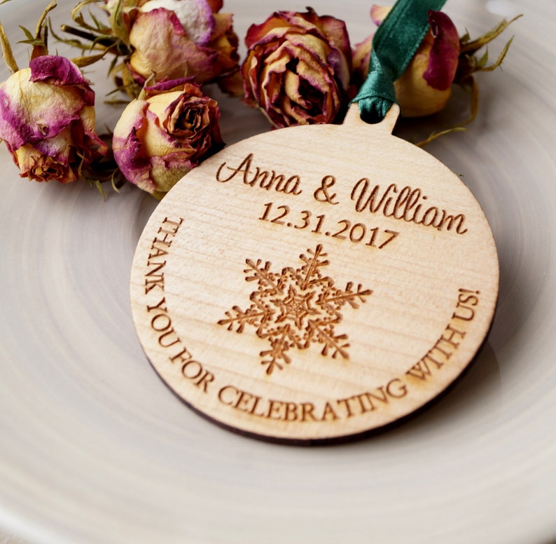 May include: A round wooden ornament with a snowflake design and the text "Anna & William 12.31.2017 Thank You For Celebrating With Us!"