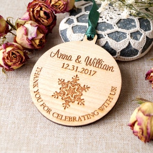 May include: A round wooden ornament with the text "Anna & William 12.31.2017 Thank you for celebrating with us!" engraved on it. A snowflake design is in the center of the ornament.