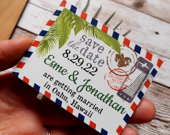 May include: Save the date card with a tropical theme. The card is white with red, blue, and white stripes around the edges. The text on the card reads "Save the date 8.29.22 Esme & Jonathan are getting married in Oahu, Hawaii".