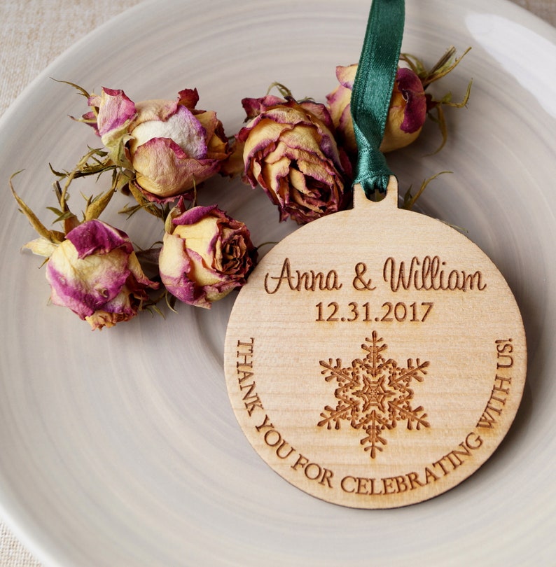 May include: A round wooden ornament with a snowflake design and the text "Anna & William 12.31.2017 Thank You For Celebrating With Us!"