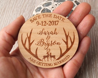 May include: A round wooden save the date magnet with a rustic design. It features a pair of antlers, two deer, and the text "Save the Date 9-12-2017 Sarah & Bryson Are Getting Married".