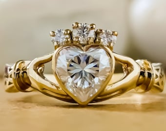 May include: A gold ring with a heart-shaped diamond and smaller diamonds on the band. The ring is a Celtic Claddagh design.