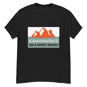 Pode incluir: Camiseta preta com um gráfico de uma cordilheira e o texto "Kananaskis Can a Donkey Smooch"
