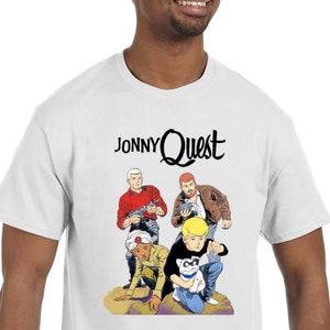 May include: White t-shirt with a cartoon image of Jonny Quest and his friends. The text "Jonny Quest" is printed in black above the image.
