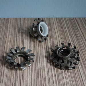 Peut inclure: Trois douilles de lampe en métal vintage avec un design à rayons unique. Une douille a un intérieur en céramique blanche. Les douilles sont disposées sur une surface en bois avec un fond bleu.