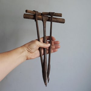Pode incluir: Três verrumas manuais antigas com cabos em T de madeira escura e desgastada, e longas hastes de ferro enferrujado com pontas em espiral na parte inferior. Estas ferramentas manuais de marcenaria apresentam sinais de uso e envelhecimento.