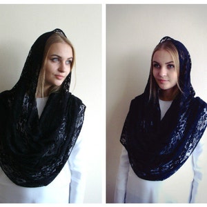 May include: A black lace shawl with a hood. The shawl is draped over a person's shoulders and head.