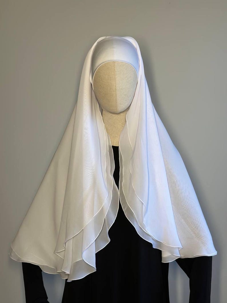 Op de afbeelding: Witte chiffon hijab met een gelaagd ontwerp. De hijab is gedrapeerd over de kop en schouders van een mannequin.