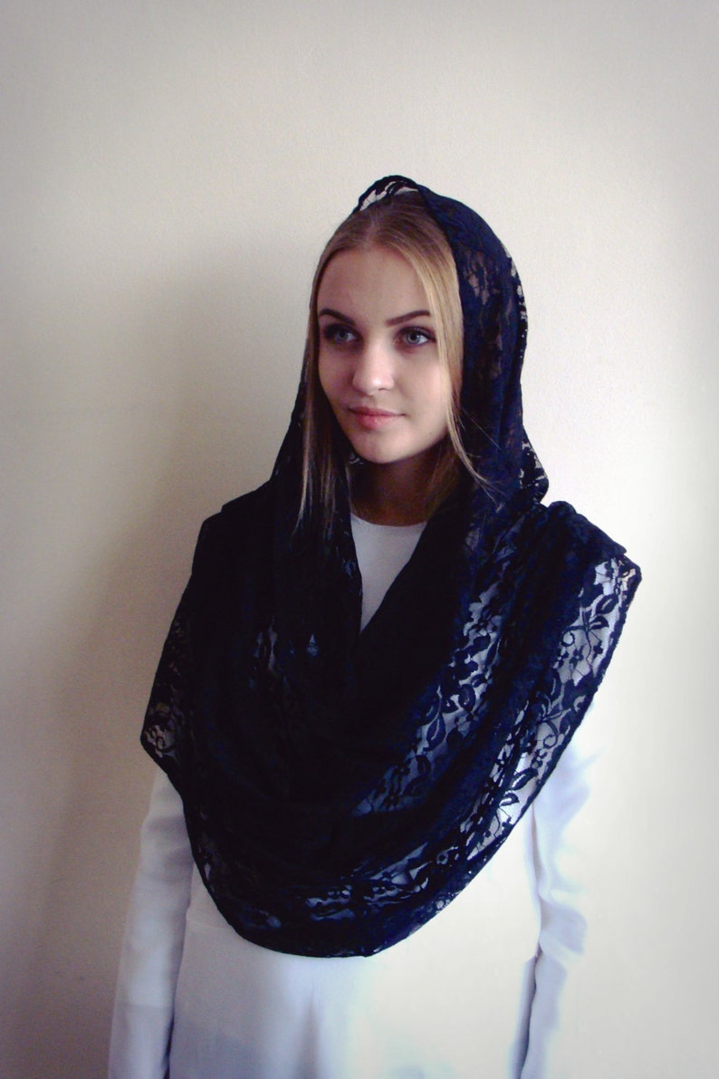 May include: A black lace shawl with a floral pattern. The shawl is draped over a person's head and shoulders.