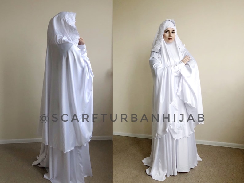 May include: White prayer dress with a long, flowing skirt and a matching head covering. The dress has a lace trim and a ruffled design. The image includes the text "@scarfturbanhijab".