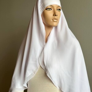 Op de afbeelding: Witte chiffon hijab met een dubbele laag en een eenvoudig ontwerp. De hijab is gemaakt van een lichtgewicht en vloeiende stof.