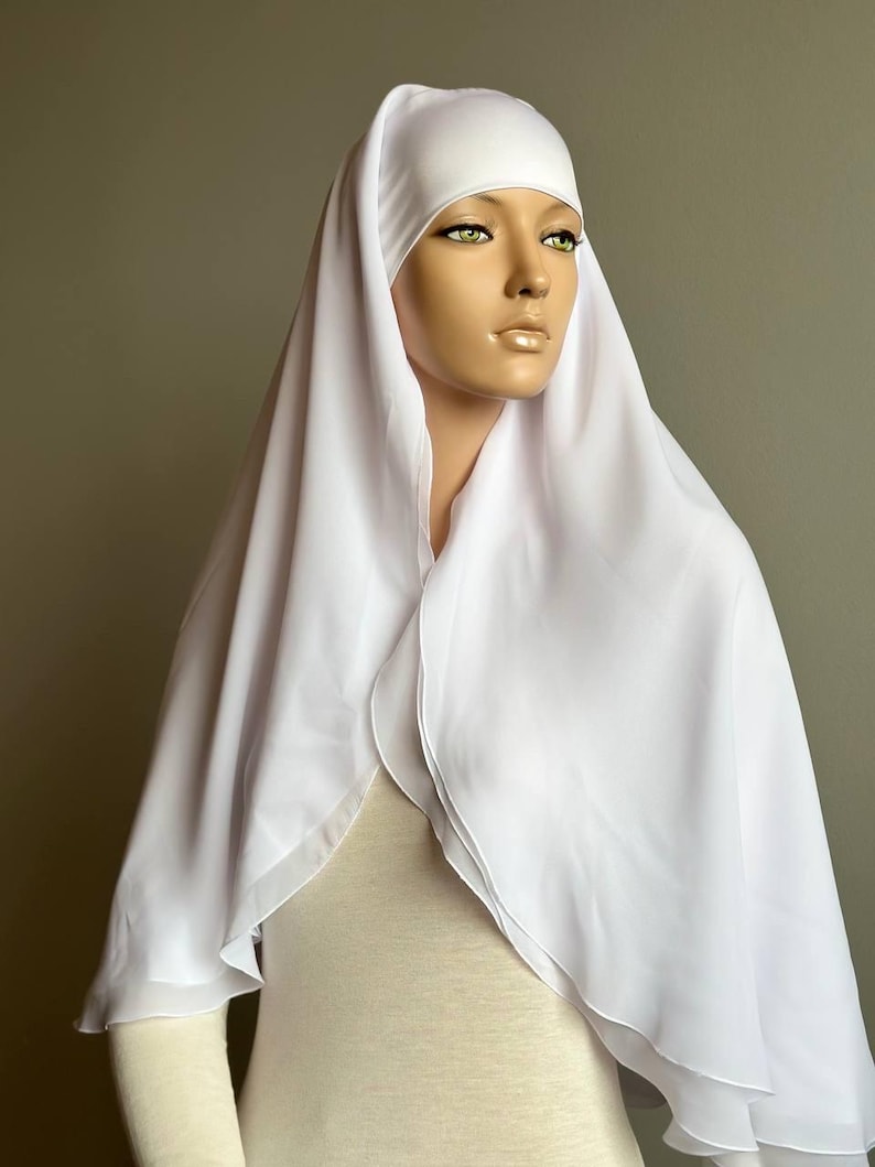 Op de afbeelding: Witte chiffon hijab met een dubbele laag en een eenvoudig ontwerp. De hijab is gemaakt van een lichtgewicht en vloeiende stof.