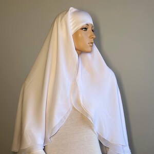 Op de afbeelding: Witte chiffon hijab met een dubbele laag en een satijnen voering. De hijab is gedrapeerd over het hoofd en de schouders van een mannequin.