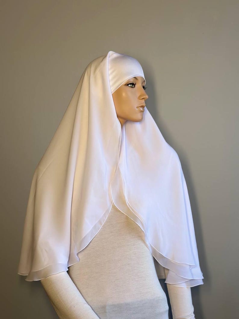 Op de afbeelding: Witte chiffon hijab met een dubbele laag en een satijnen voering. De hijab is gedrapeerd over het hoofd en de schouders van een mannequin.