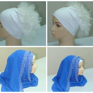 May include: Two mannequins wearing different styles of headscarves. The first mannequin is wearing a white headscarf with a white tulle puff on top. The second mannequin is wearing a blue headscarf with a white beaded trim.